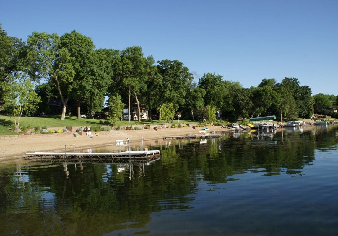 Docks and beach area on lake with trees in background.